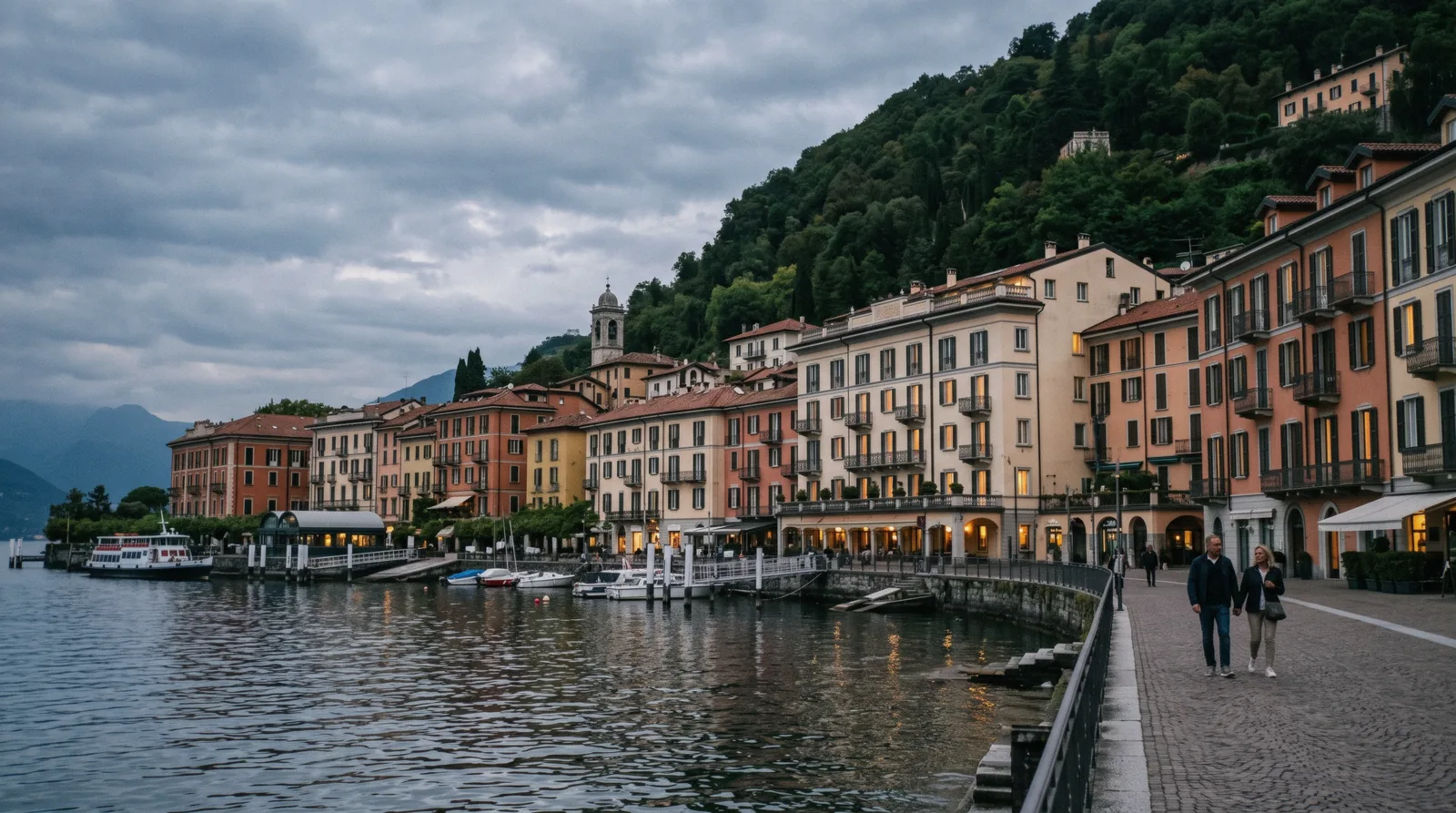 Lakefront hotel facades along the shore in Como city at dusk with the Brunate hill behind, choosing Como hotels