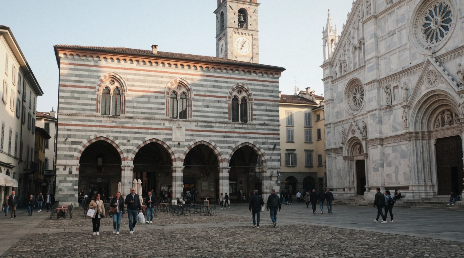 The striped grey, white and red stone façade and pointed arches of the Broletto beside Como Cathedral on Piazza Duomo, the Broletto Como in Como, Italy