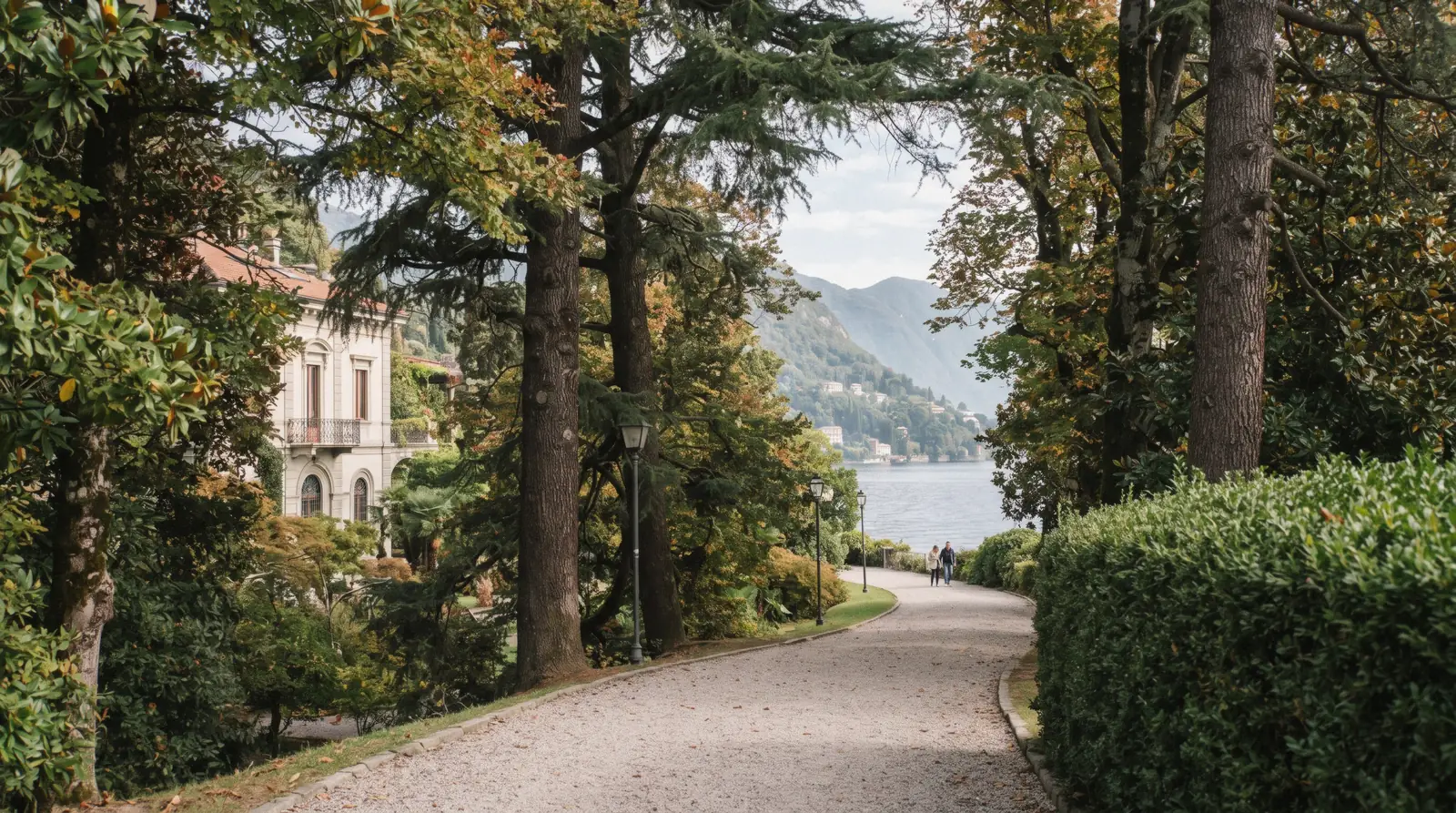 A gravel path through a lakeside villa park west of Como on the Como to Cernobbio walk, with the lake and hills beyond