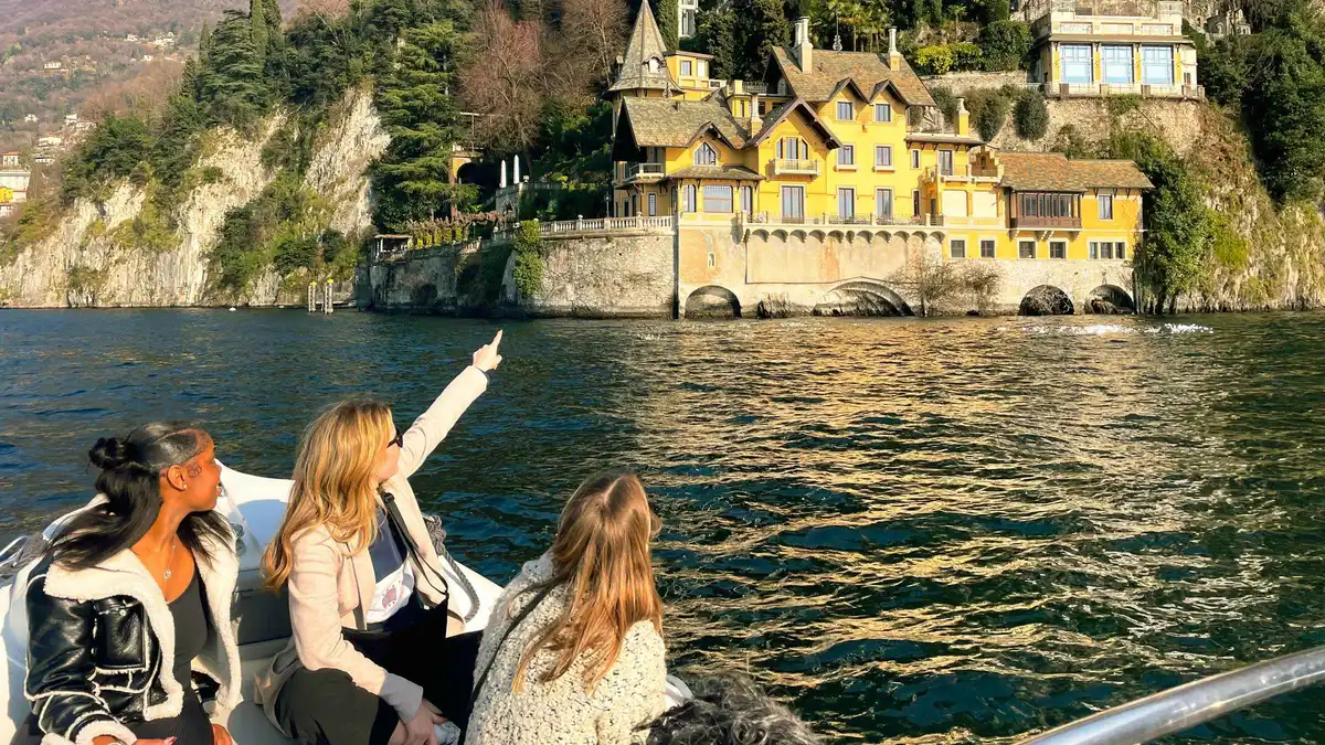 A wooden Venetian taxi boat crossing Lake Como past lakeside villas on a Como boat tour in Como, Italy