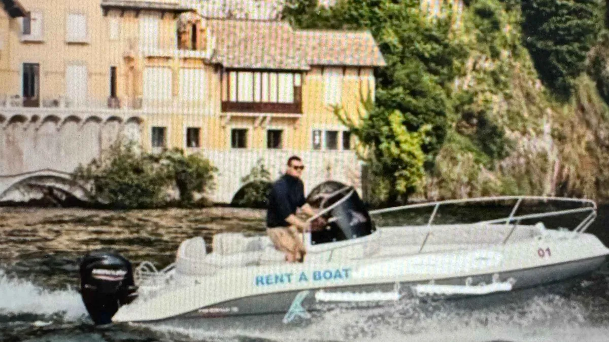 A small self-drive motorboat idling near the Como shoreline on a self-drive boat rental in Como, Italy
