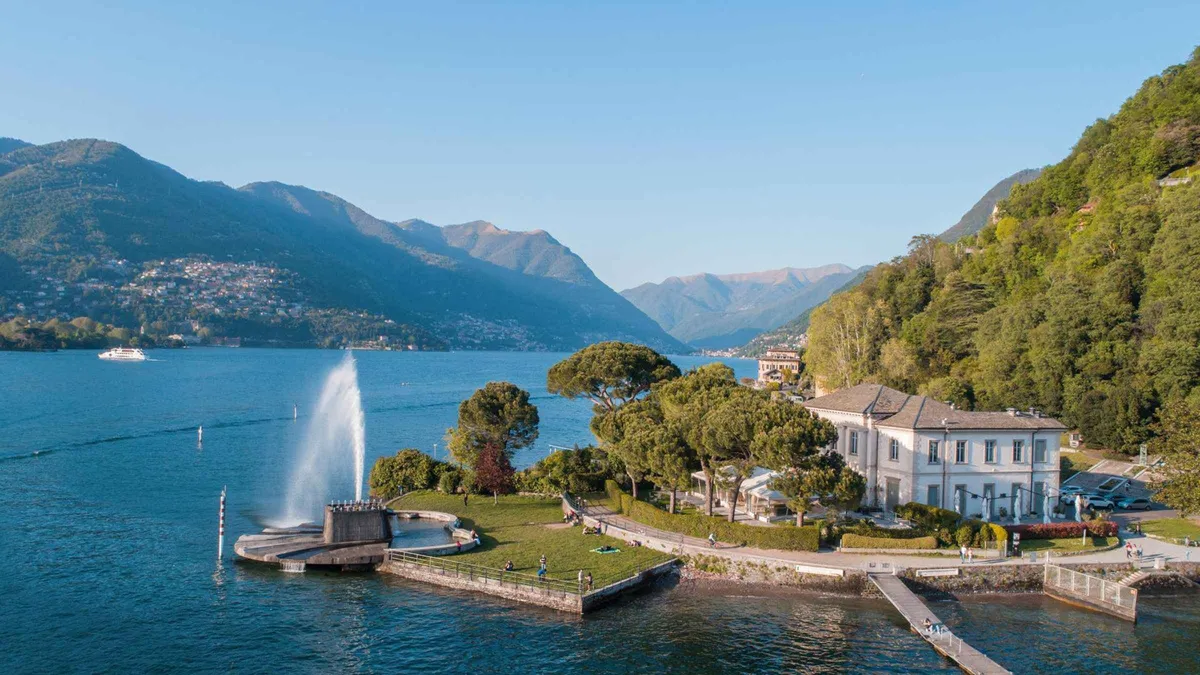 A shared boat sailing close to Villa d'Este's gardens on a Lake Como boat tour in Como, Italy
