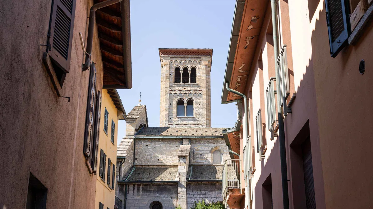 A small guided group walking past Como's Romanesque cathedral facade on a Como guided city tour in Como, Italy