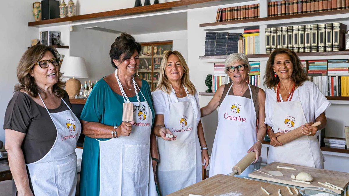 Hands shaping fresh ravioli dough on a floured table on a pasta cooking class in Como, Italy