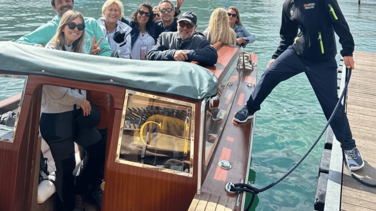 Passengers aboard a wooden Venetian taxi boat with an audio guide on a Lake Como boat tour in Como, Italy